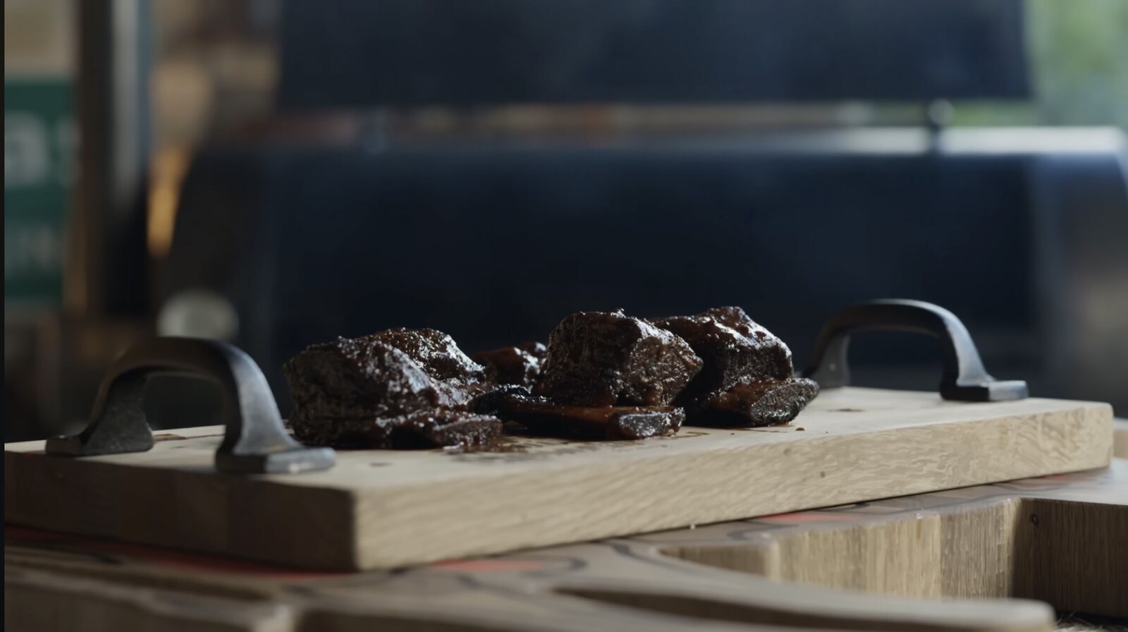 Smoked beef short ribs resting on a cutting board near the pit