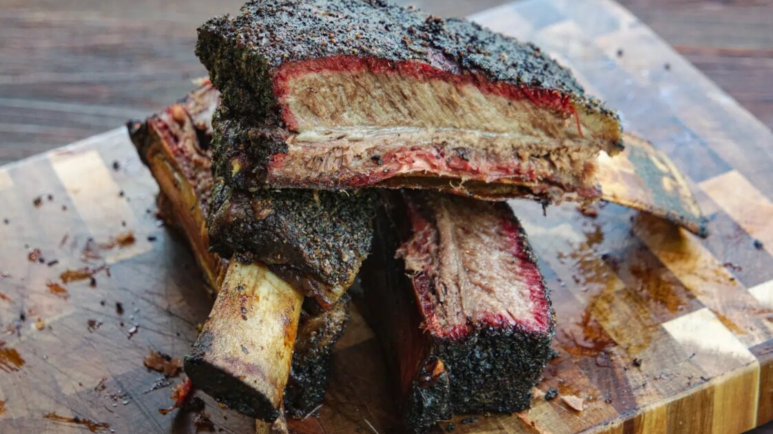 Smoked beef rib rack cut into large ribs with dark bark and smoke ring