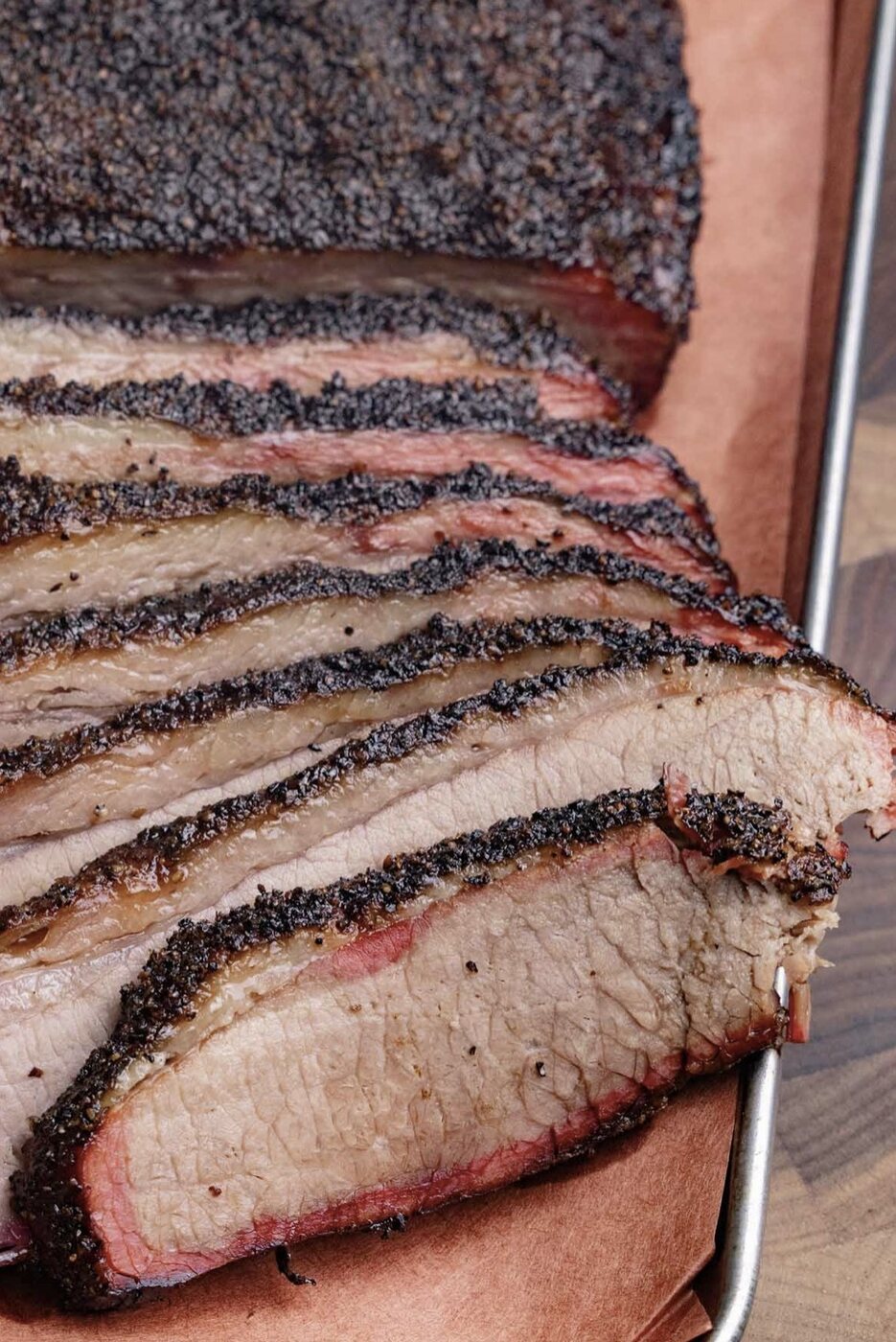 Sliced whole beef brisket showing dark bark and smoke ring