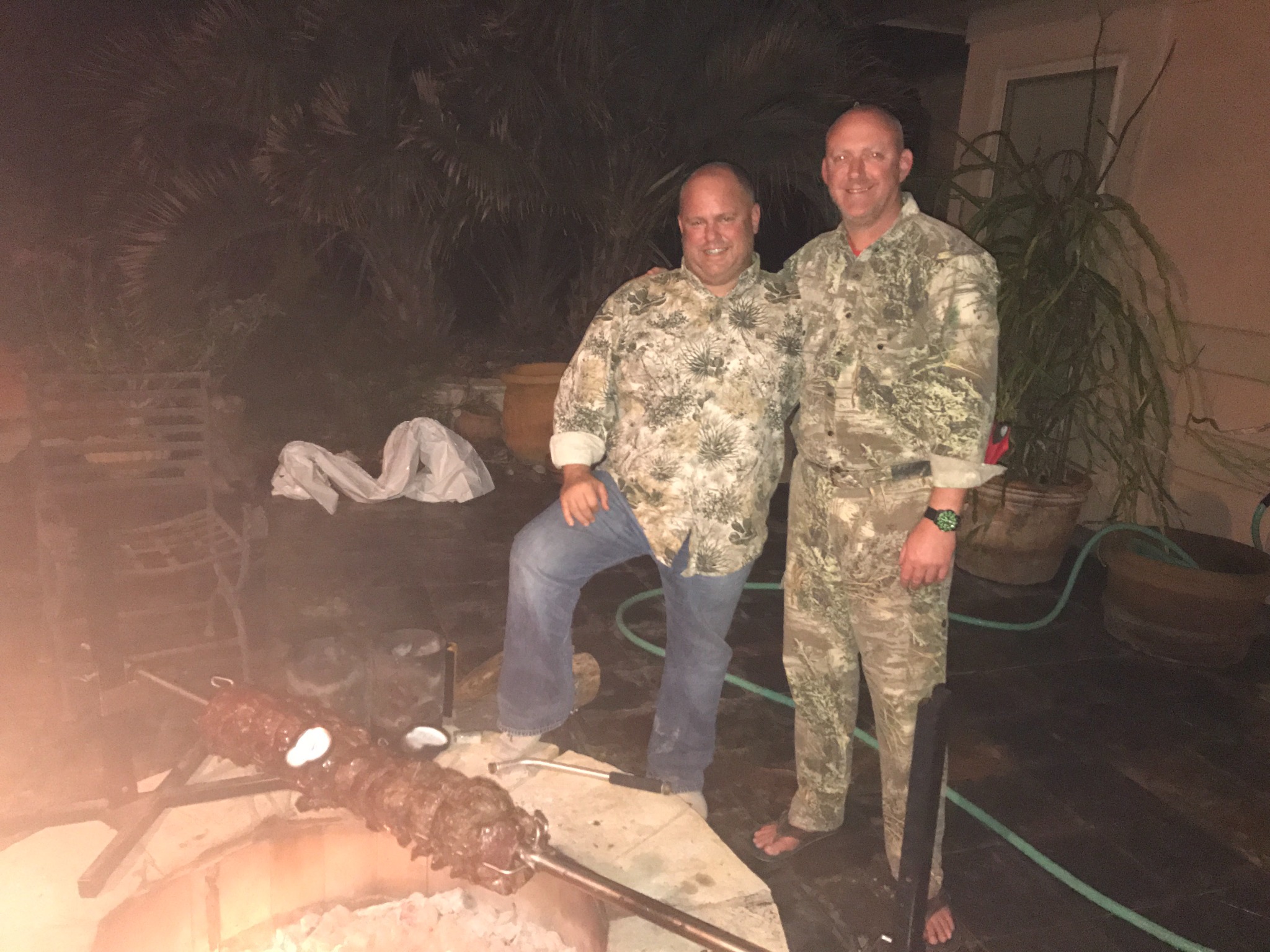 Jeff and Jeff beside a pig roast at the McCoy Ranch